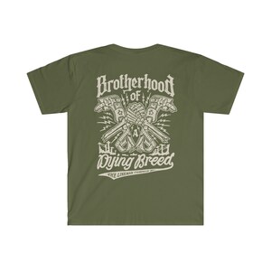 Op de afbeelding: Een groen T-shirt met een witte grafische print van twee skeletachtige handen die een moersleutel vasthouden. De grafiek luidt "Brotherhood of a Dying Breed" en "The Lineman Company".