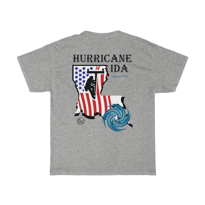 Pu&ograve; includere: Una maglietta grigio melange con un design grafico che commemora l'uragano Ida. Il design include il testo "HURRICANE IDA August 2021" sopra una mappa stilizzata della Louisiana con un design a bandiera americana e una grafica blu dell'uragano.