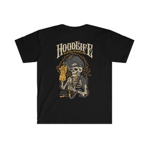 Pode incluir: Camiseta preta com um gr&aacute;fico de um esqueleto usando uma m&aacute;scara de solda e segurando um ma&ccedil;arico de solda. O texto "HOODLIFE BLUE COLLAR REBELLION ESTD. MMXX" est&aacute; impresso na camiseta.
