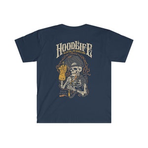 Pode incluir: Camiseta azul marinho com um gr&aacute;fico de um esqueleto usando uma m&aacute;scara de solda e segurando um ma&ccedil;arico de solda. O texto "HOODLIFE BLUE COLLAR REBELLION ESTD. MMXX" est&aacute; impresso na camiseta.