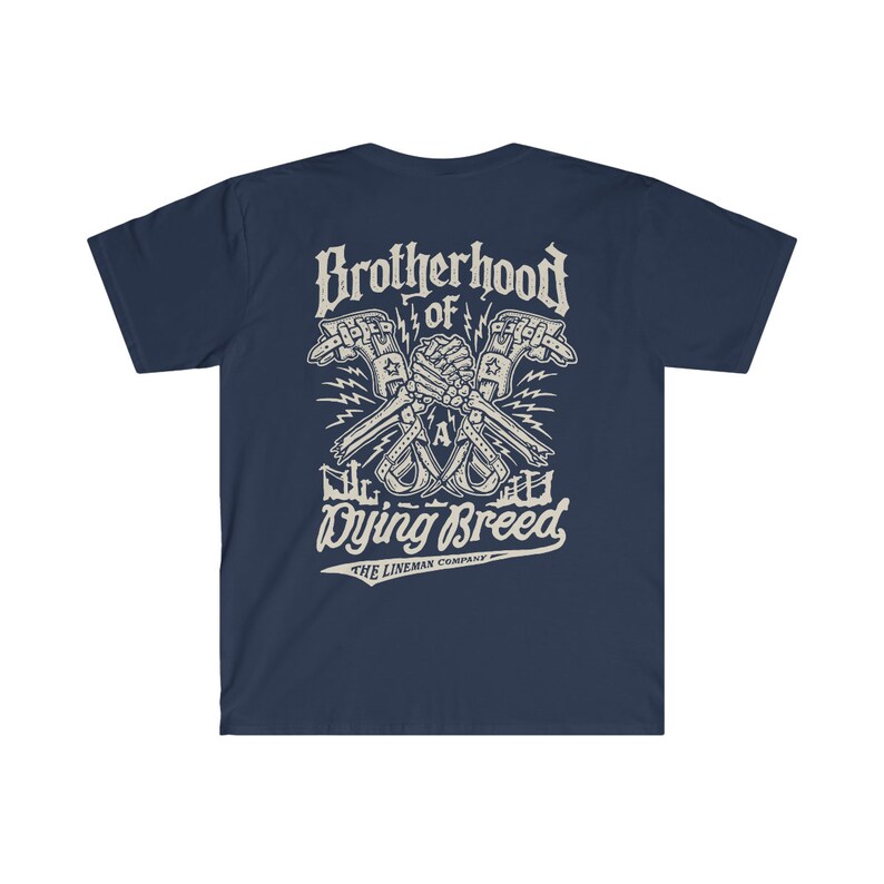 Op de afbeelding: Donkerblauw T-shirt met een witte afbeelding van twee skeletachtige handen die een moersleutel vasthouden, met de tekst "Brotherhood of a Dying Breed" en "The Lineman Company" eronder.