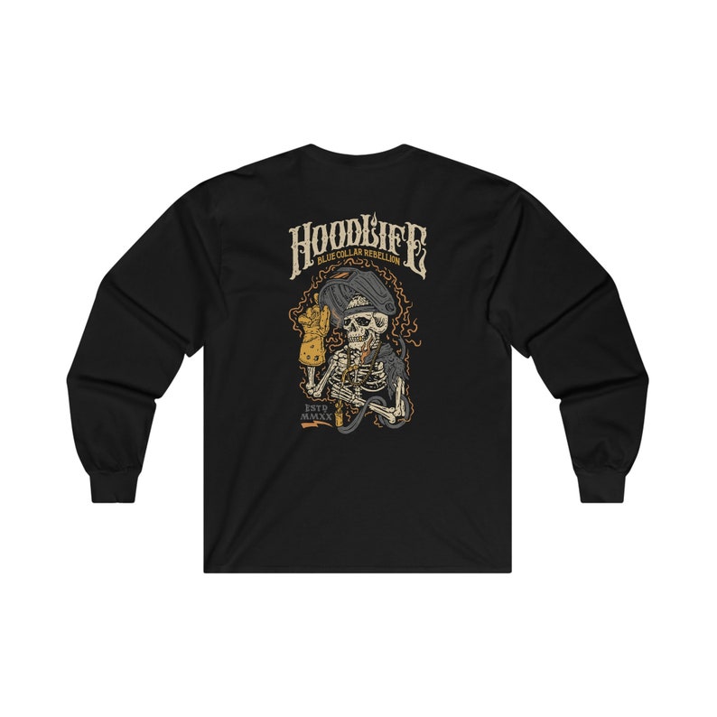 Pode incluir: Camiseta preta de manga comprida com um gr&aacute;fico de um esqueleto usando uma m&aacute;scara de soldador e segurando um ma&ccedil;arico de solda. O texto "HOODLIFE BLUE COLLAR REBELLION ESTD. MMXX" est&aacute; impresso na camiseta.
