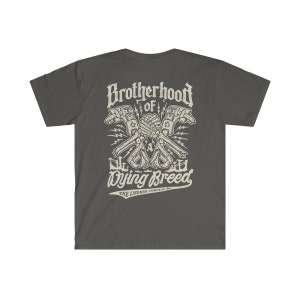 Op de afbeelding: Een donkergrijs T-shirt met een wit grafisch ontwerp van twee gekruiste handen met de tekst "Brotherhood of a Dying Breed" en "The Lineman Company" eronder.