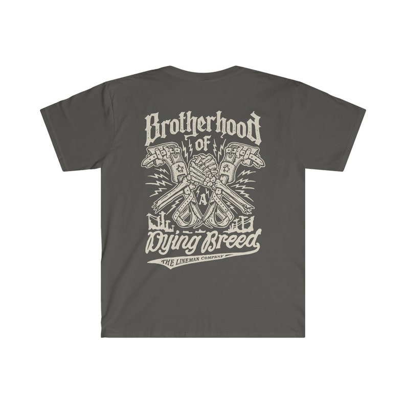 Op de afbeelding: Een donkergrijs T-shirt met een wit grafisch ontwerp van twee gekruiste handen met de tekst "Brotherhood of a Dying Breed" en "The Lineman Company" eronder.