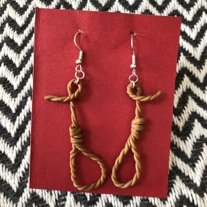 May include: A pair of brown rope earrings with silver hooks. The rope is tied in a noose shape.