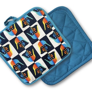 May include: Two square pot holders. One features a checkered pattern with a character design in black, blue, orange, and white. The other is solid blue with a quilted design. Both have blue trim and a hanging loop.