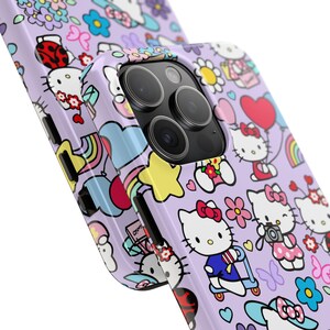 May include: A purple phone case with a repeating pattern of Hello Kitty characters, rainbows, stars, and hearts. The case has a cutout for the camera lens.