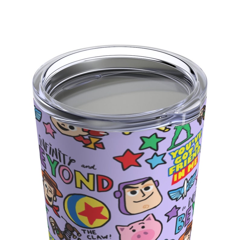 K&ouml;nnte beinhalten: Ein lilafarbener Edelstahlbecher mit einem bunten Muster aus Toy Story-Charakteren und S&auml;tzen, darunter "Unendlich und dar&uuml;ber hinaus", "Du hast einen Freund in mir" und "Die Klammer!"