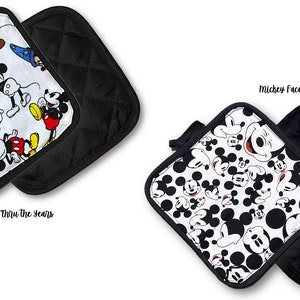 May include: Two black and white quilted pot holders with a Mickey Mouse theme. One pot holder features Mickey Mouse through the years and the other features Mickey Mouse faces.  The text "Mickey Faces" and "Mickey Thru the Years" is printed below each pot holder.