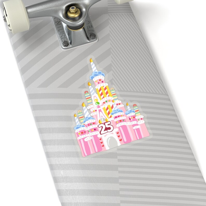 May include: A pink and white sticker of a birthday cake version of Cinderella's castle with the number 25 on the front. The castle is decorated with candles, sprinkles, and hearts.