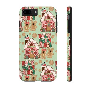 May include: A phone case with a repeating pattern of gingerbread houses, gingerbread people, and snowflakes on a light green background. The text "Holly Vibes" is featured in red, green, and white. The case is shown from the front and side.