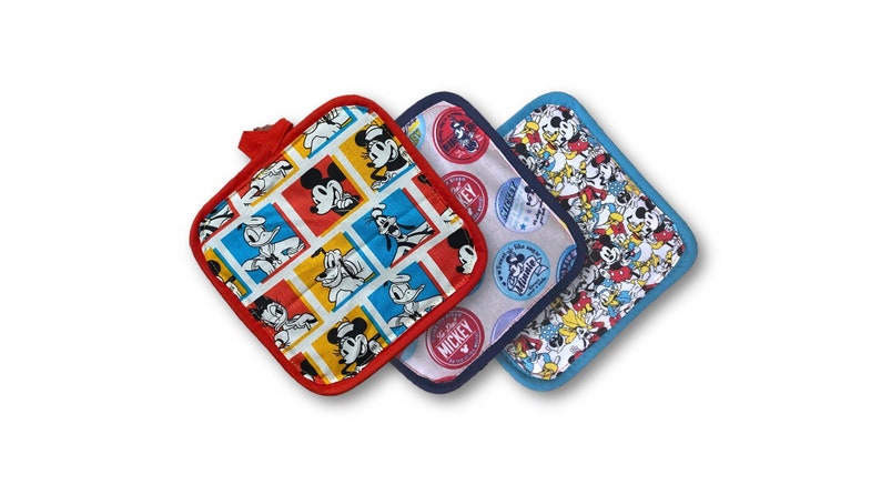 May include: Three square-shaped pot holders with a red, blue, and light blue border. The pot holders feature a white background with a repeating pattern of Mickey Mouse and other Disney characters. The red pot holder has a pattern of Mickey Mouse in squares. The blue pot holder has a pattern of Mickey Mouse heads in circles. The light blue pot holder has a pattern of Mickey Mouse and other Disney characters in various poses.