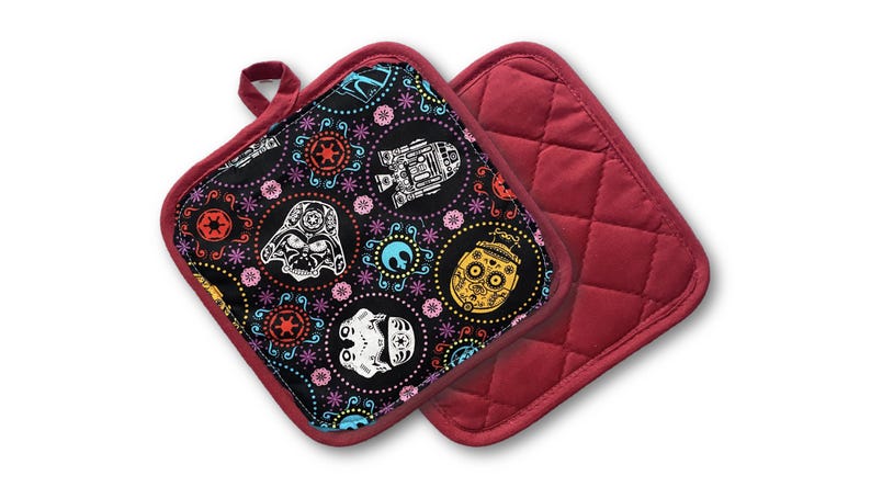 May include: Two square pot holders. One features a black background with colorful Day of the Dead-style Star Wars character designs. The other is solid red with a quilted pattern. Both have red trim and a hanging loop.