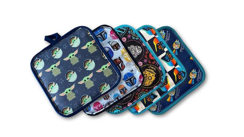 May include: A collection of five square pot holders with various Star Wars-themed patterns. Designs include Baby Yoda, Boba Fett, and other characters. Each pot holder has a dark blue border and a loop for hanging.