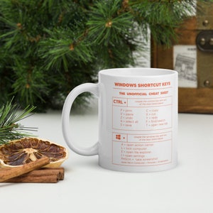 May include: White ceramic mug with a red and white design. The mug features a list of Windows shortcut keys with the text "Windows Shortcut Keys" and "The Unofficial Cheat Sheet".