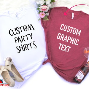 May include: Two t-shirts, one white and one maroon, with the text "Custom Party Shirts" and "Custom Graphic Text" printed on them. The shirts are laid out on a white surface with flowers and a bottle of sparkling wine.
