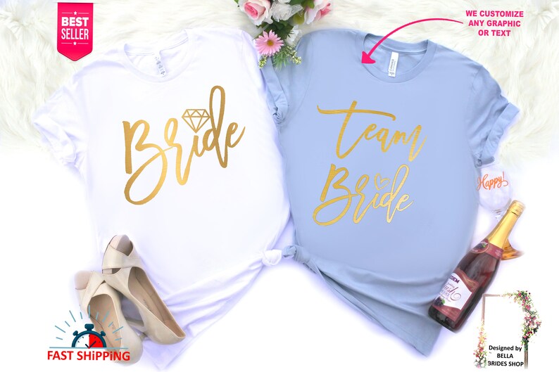 May include: Two t-shirts, one white and one light blue, with gold lettering. The white shirt says "Bride" with a diamond graphic. The light blue shirt says "Team Bride".