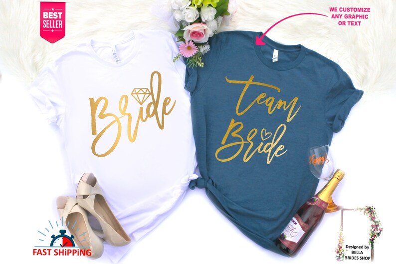 May include: Two white t-shirts with gold lettering. One shirt says "Bride" with a diamond graphic. The other shirt says "Team Bride" with a heart graphic.