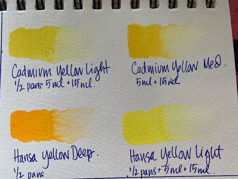May include: Four watercolor paint swatches on a white paper background. The swatches are labeled with the names and amounts of paint used. The top left swatch is labeled "Cadmium Yellow Light 1/2 pans 5 ml + 15 ml.", the top right swatch is labeled "Cadmium Yellow Med. 5 ml + 15 ml.", the bottom left swatch is labeled "Hansa Yellow Deep. 1/2 pans", and the bottom right swatch is labeled "Hansa Yellow Light 1/2 pans + 5 ml + 15 ml."
