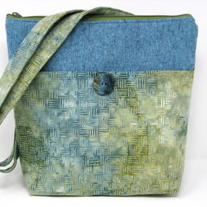 May include: A blue and green shoulder bag with a woven pattern on the lower half and a solid blue top. The bag has a long strap and a button closure. The zipper is green.