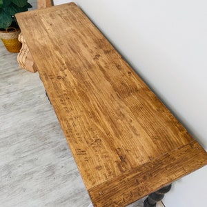 Peut inclure: Une console en bois longue avec une finition en bois naturel. La table a un dessus rectangulaire simple et une base sculpt&eacute;e et enroul&eacute;e.