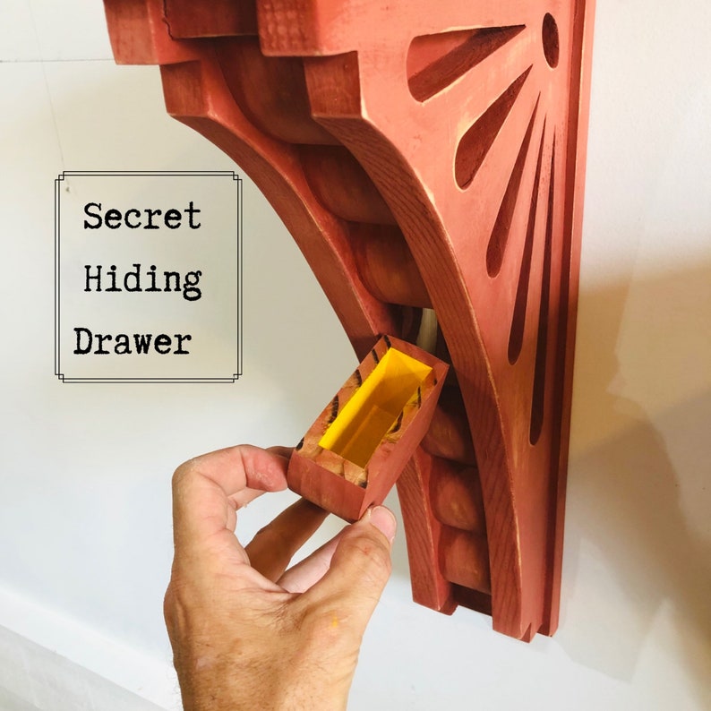 May include: A red wooden wall shelf with a secret hiding drawer. The drawer is open and reveals a yellow interior. The text "Secret Hiding Drawer" is written on a white background.