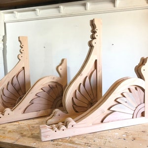May include: Three unfinished wooden corbels with intricate floral designs. The corbels are stacked on top of each other and have a natural wood finish.