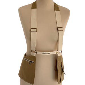 May include: A tan canvas bag with two large pockets and a white strap. The bag has a white label that says "MOVER'S BAG".