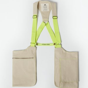 May include: A beige canvas utility bag with two pockets and neon yellow adjustable straps. The bag has a label that reads "MOVER'S BAG".
