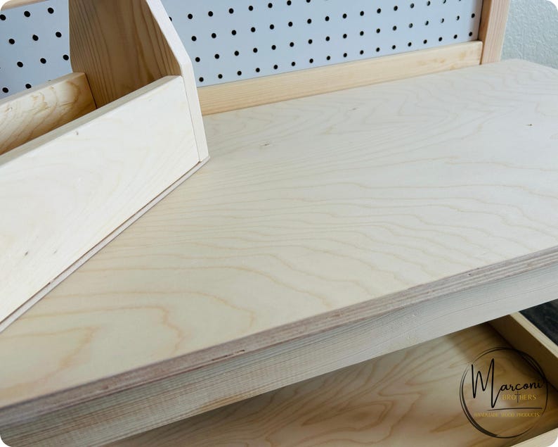 May include: A light-colored wooden desk with a built-in organizer and a drawer. The desk has a natural wood grain finish and a pegboard back. The organizer has multiple compartments for storing items. The drawer has a circular logo.