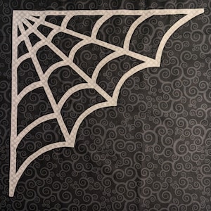 May include: A white spiderweb design on a black fabric with a swirling pattern. The spiderweb is in the corner of the fabric.
