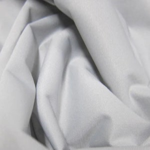 Könnte beinhalten: Nahaufnahme eines glatten, weißen Stoffes mit einer dezenten Textur. Der Stoff ist gefaltet und drapiert und erzeugt weiche Falten und Kurven.