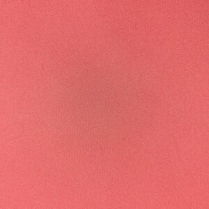 Könnte beinhalten: Ein einfarbiger korallenfarbener Stoff mit einer glatten, leicht strukturierten Oberfläche.