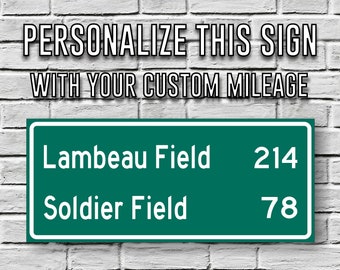 May include: A personalized green sign with white text against a brick wall. The sign reads "Personalize this sign with your custom mileage." Below, it lists "Lambeau Field" at 214 miles and "Soldier Field" at 78 miles.