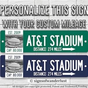 May include: Two rectangular metal signs featuring the text AT&T STADIUM, DISTANCE: 274 MILES, and a white arrow. Each sign includes a black and white image of the stadium with the text EST. 2009 and CAP. 80,000. One sign is green, the other is navy blue.