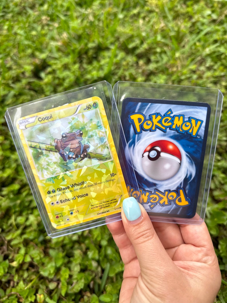 K&ouml;nnte beinhalten: Zwei Pok&eacute;mon-Sammelkarten. Die erste Karte ist gelb und zeigt einen Comic-Frosch mit dem Text "BASIC Coqui 60" und den Attacken "Grass Whistle" und "Echoed Voice". Die zweite Karte ist blau und zeigt das Pok&eacute;mon-Logo und einen Pok&eacute;ball.