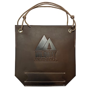 May include: A brown leather tote bag with a logo that reads "WILDWAY BUSHCRAFT". The bag has a rectangular shape with a handle made of a brown cord. The logo features a mountain and tree design.