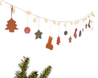 May include: A string of Christmas ornaments with a variety of shapes, including stars, trees, and stockings. The ornaments are made of leather and are painted in shades of brown, red, and green. The string is strung with white lights.