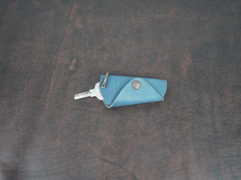 May include: A blue leather key holder with a metal ring and a key inside.