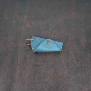 May include: A blue leather key holder with a metal ring and a small metal button.