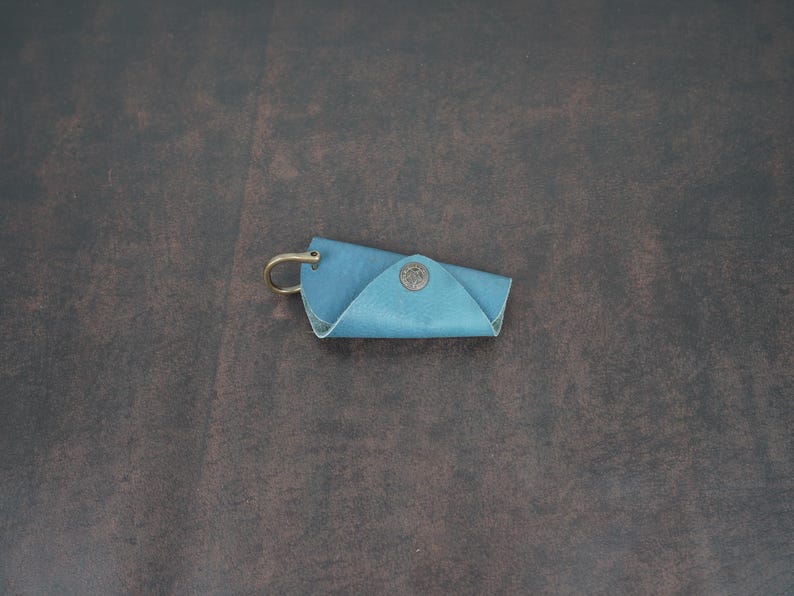 May include: A blue leather key holder with a metal ring and a small metal button.