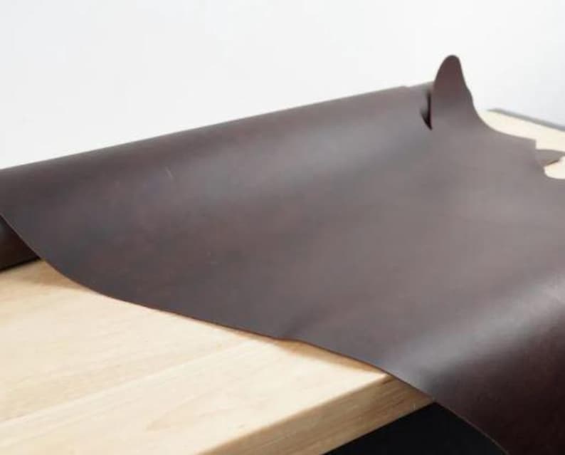 May include: A roll of dark brown leather, unfurled on a wooden surface.