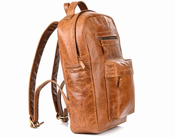 Könnte beinhalten: Ein hellbrauner Lederrucksack mit strukturierter, abgenutzter Oberfläche, einem Tragegriff, verstellbaren Schultergurten mit Metallschnallen, einem Hauptfach mit Reißverschluss und einer kleineren Fronttasche mit Reißverschluss.