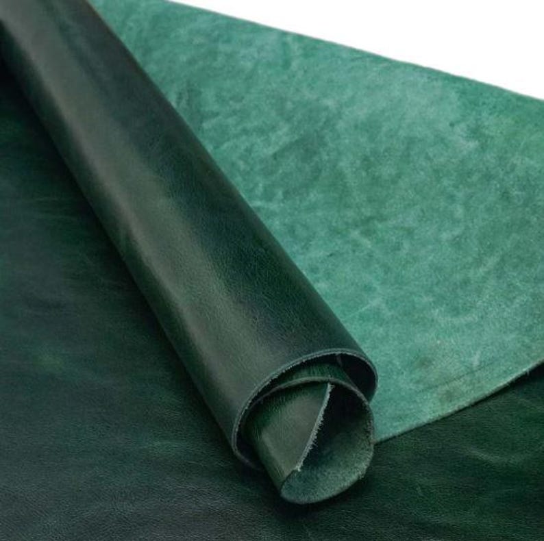 May include: A close-up of a roll of dark green leather. The leather has a smooth, textured surface and is folded over on itself.