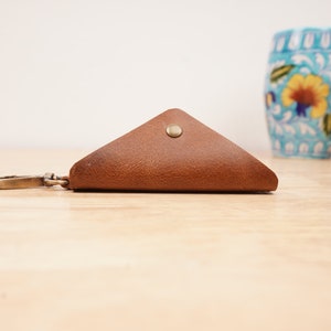 May include: A brown leather triangle-shaped key chain with a metal clasp and a button closure.