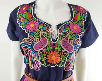May include: A navy blue embroidered blouse with a lace-up neckline and colorful floral and bird designs.
