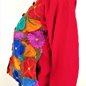 May include: A red embroidered jacket with colorful floral designs. The jacket has a button closure and pockets.