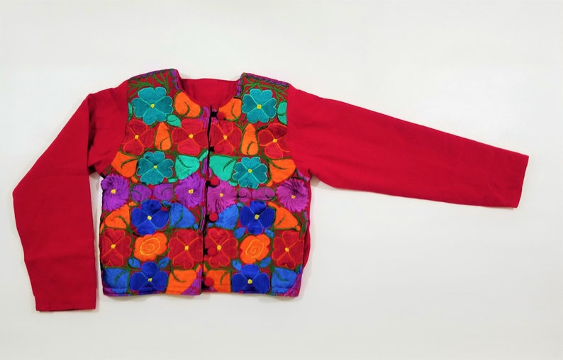 May include: A red embroidered jacket with a floral pattern in shades of blue, green, orange, purple, and red. The jacket has a button closure and long sleeves.