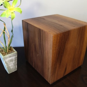 Op de afbeelding: Een houten kubus met een rijke bruine houtnerf. De kubus is gemaakt van massief hout en heeft een glad, gepolijst oppervlak.