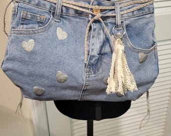 Handgemaakte tas van gerecyclede spijkerstof – Crossbodytas van gerecycled denim met zilveren hartjesprint en riem met studs.